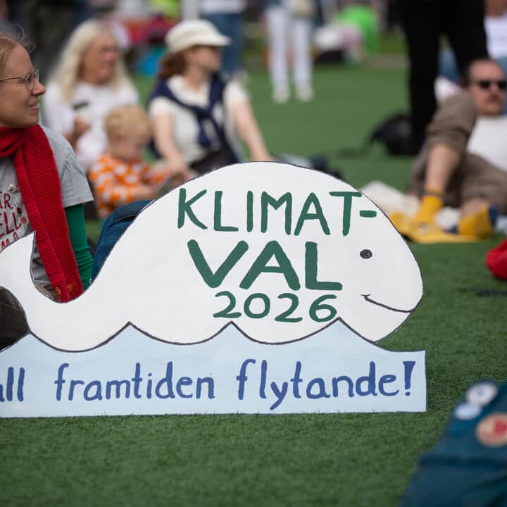 Bilden visar en grupp människor som deltar i en klimatdemonstration. I förgrunden finns en skylt ...